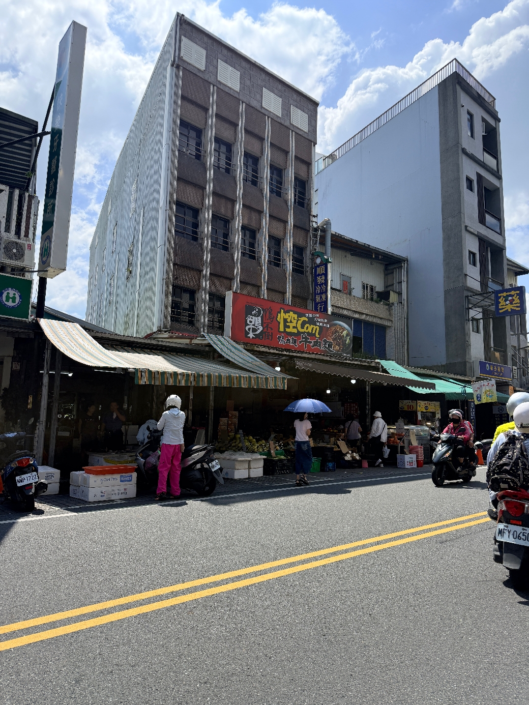 礁溪舊路中山路二段76號菜市場外街景，陽光明媚，多名人車在市場周圍活動。