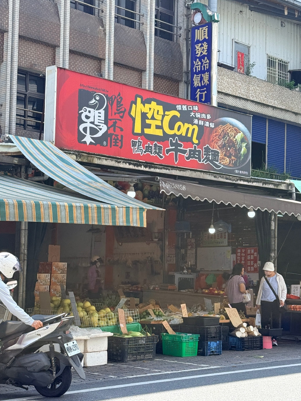 礁溪舊路中山路二段76號菜市場外觀，攤位前擺放多種蔬果，前方有一名騎機車男子。