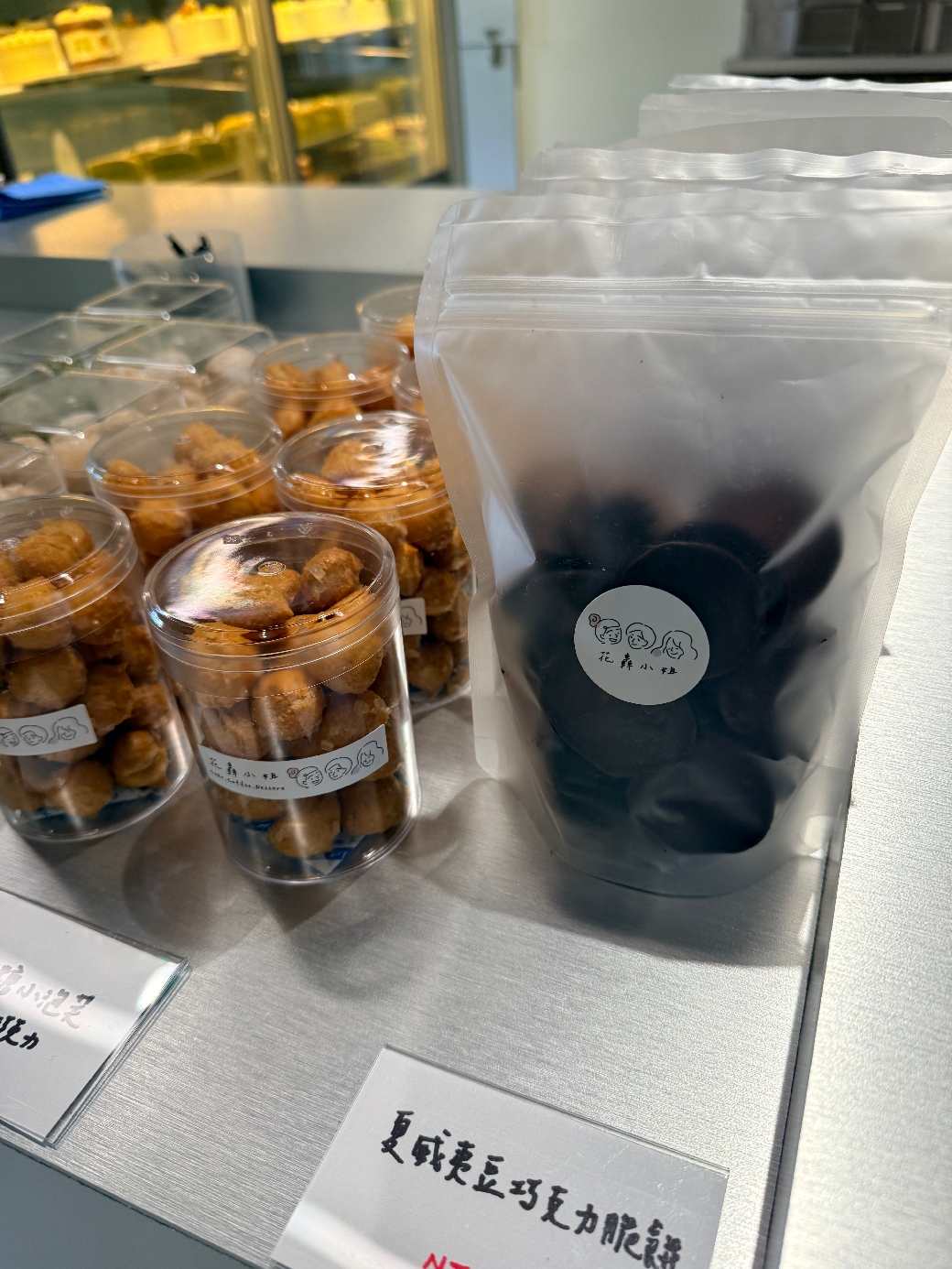 展示檯上的透明罐裝與夾鏈袋裝點心，包裝上有店名標籤